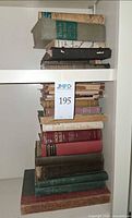 Tall stack of vintage hardcover books showing spines including The Holy Bible and others