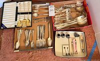 Overview of entire lot showing assorted flatware, serving pieces, gold servers in case, knives and holders