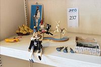 Shelf view showing carousel animals, ship model, tile plaque, Evzone figure, metal soldiers, clown doll