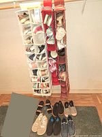 Full view of two hanging organizers filled with shoes and additional pairs on floor