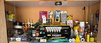 Cabinet shelf loaded with assorted bulbs, sealants, tapes, fasteners and other hardware items