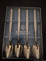 Boxed set of four gold plated teaspoons labeled Community Silverplate