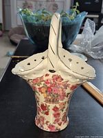 Front view of porcelain basket showing cherub and floral pattern, handle, pierced rim