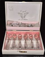 Open box displaying six wrapped teaspoons and two wrapped serving utensils