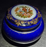 Closed trinket box showing cobalt glaze, gilt border, figural medallion