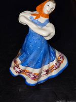 Front view of porcelain folk dancer figurine showing colors and pose
