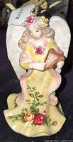 Front view of porcelain angel ornament showing gown, harp and floral pattern