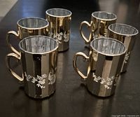 Six mirrored glass cups with gold trim displayed on table
