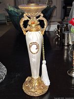 Full view front of decorative candlestick showing cameo, tassel, gold accents