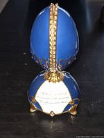 Closed blue and gold musical egg on stand