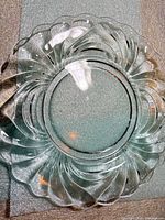Top view of clear glass plate showing swirl design and scalloped rim