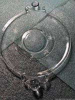 clear glass plate showing teardrop handles and dotted ring