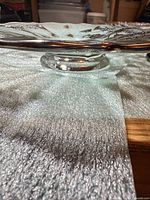 Side view showing pedestal foot, clear glass, textured surface under plate