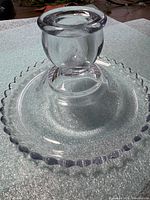 Perspective view showing entire clear glass Candlewick candle holder with beaded rim and pedestal