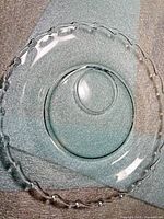 Overhead view of clear glass plate showing full form and teardrop rim
