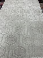 Full view of light grey hexagon-pattern rug surface