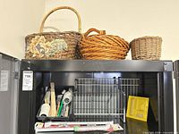 three baskets atop black cabinet, interior showing paint tools