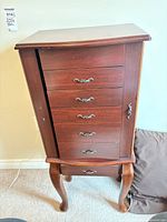 Full view of jewelry armoire showing drawers, side door, cabriole legs