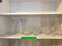 Cabinet shelf showing two vases, various short and tall cut crystal glasses