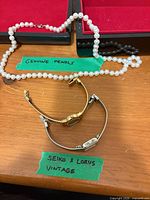 Pearl necklace with two wristwatches on table