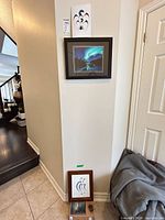 Wall view showing framed aurora borealis print, unframed Bignell card above, framed Cyrette print below