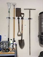 Wall-mounted view of five long-handled garden tools