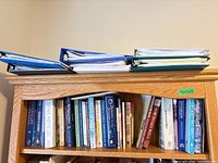Top shelf of bookcase showing binders and span of book spines