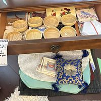 Drawer view with wood coasters, ceramic stack, fabric sachets and decorative pillow