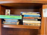Books and acrylic paperweight arranged on wooden shelf