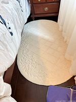 Top view of ivory oval rug beside bed showing embossed pattern