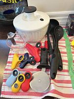 lot overview showing salad spinner, utensils, pizza cutter parts, measuring cup, six bag clips