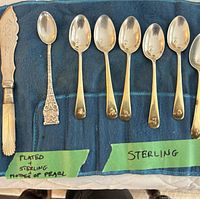 Full set showing six sterling spoons, one silver-plated spoon, mother-of-pearl cheese knife