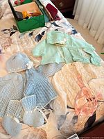Overview of all hand-knit baby garments on bed