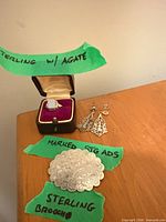 Full view of ring in presentation box, brooch and earrings with identifying labels