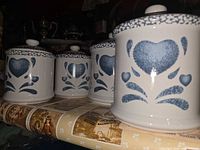 Four blue and white splatterware canisters lined up with lids on