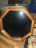 Front view of octagonal wood frame with glass and felt backing showing four circular recesses