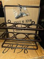 front view of metal two-tier spice rack, screws in bag, box in background