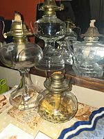 Group shot of four clear glass oil lamps with brass burners
