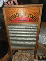 Front view of Sunnyland washboard showing brand graphic, wood frame, galvanized surface