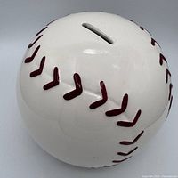 Full view of ceramic baseball coin bank showing coin slot and red stitching