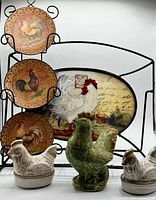 Front view showing stand, three small rooster plates, oval platter, two white hen dishes, green rooster figurine