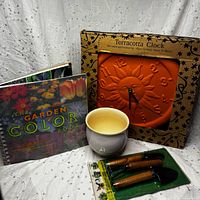 All items grouped: boxed terracotta clock, garden book, ceramic planter, sealed hand tools
