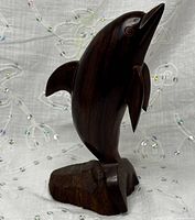 Front view of polished wood dolphin sculpture on base