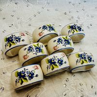 Top view of eight ceramic napkin rings showing floral decoration and blue trim