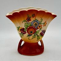 Front view showing floral motif, scalloped rim, ombré glaze, footed base
