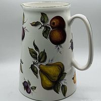 Front view of ceramic pitcher displaying pear, plum and apple graphics