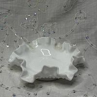 Top view of white milk glass hobnail dish showing ruffled rim
