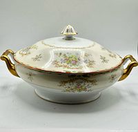 Front view of covered porcelain tureen with gold handles