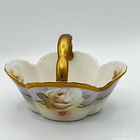 Top view of porcelain basket showing rose motif, scalloped rim, gold handle