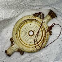 Front view of stoneware ring canteen showing overall form and leather cord